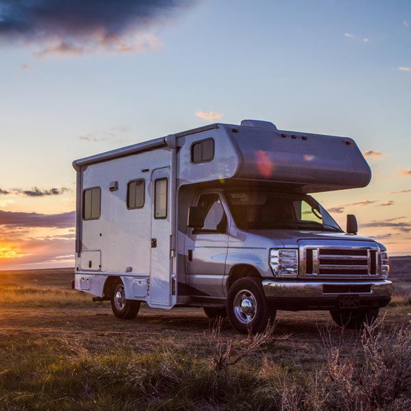 RV parked in field at sunset