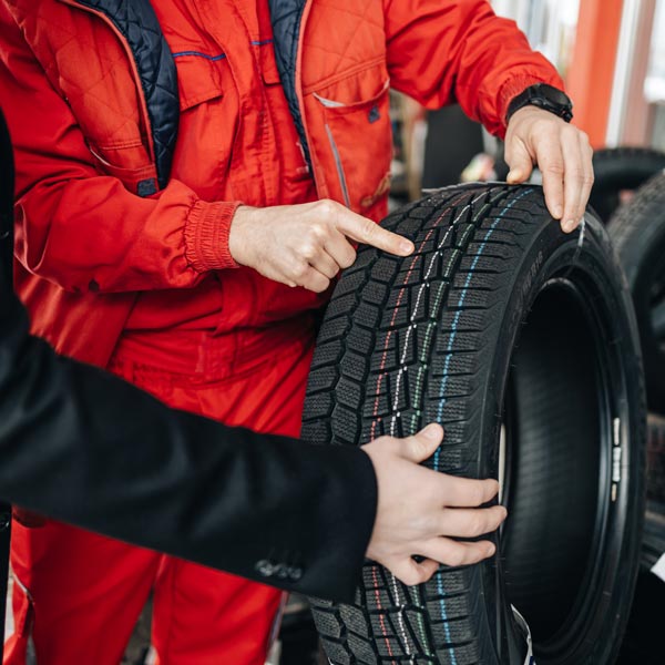 mechanic pointing to treads on new tire