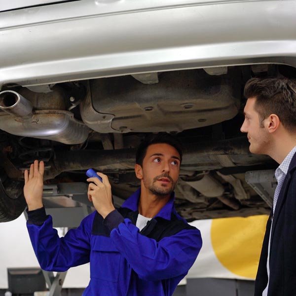 mechanic pointing out issues to customer under car